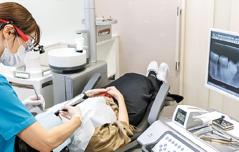 [写真] 「ダイアグノデント ペン」で測定中の藤井さん