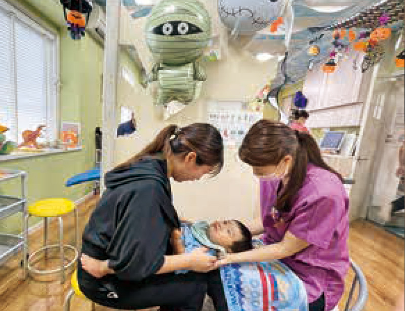 [写真] 保護者の膝の上でリラックスしながら健診を受ける様子